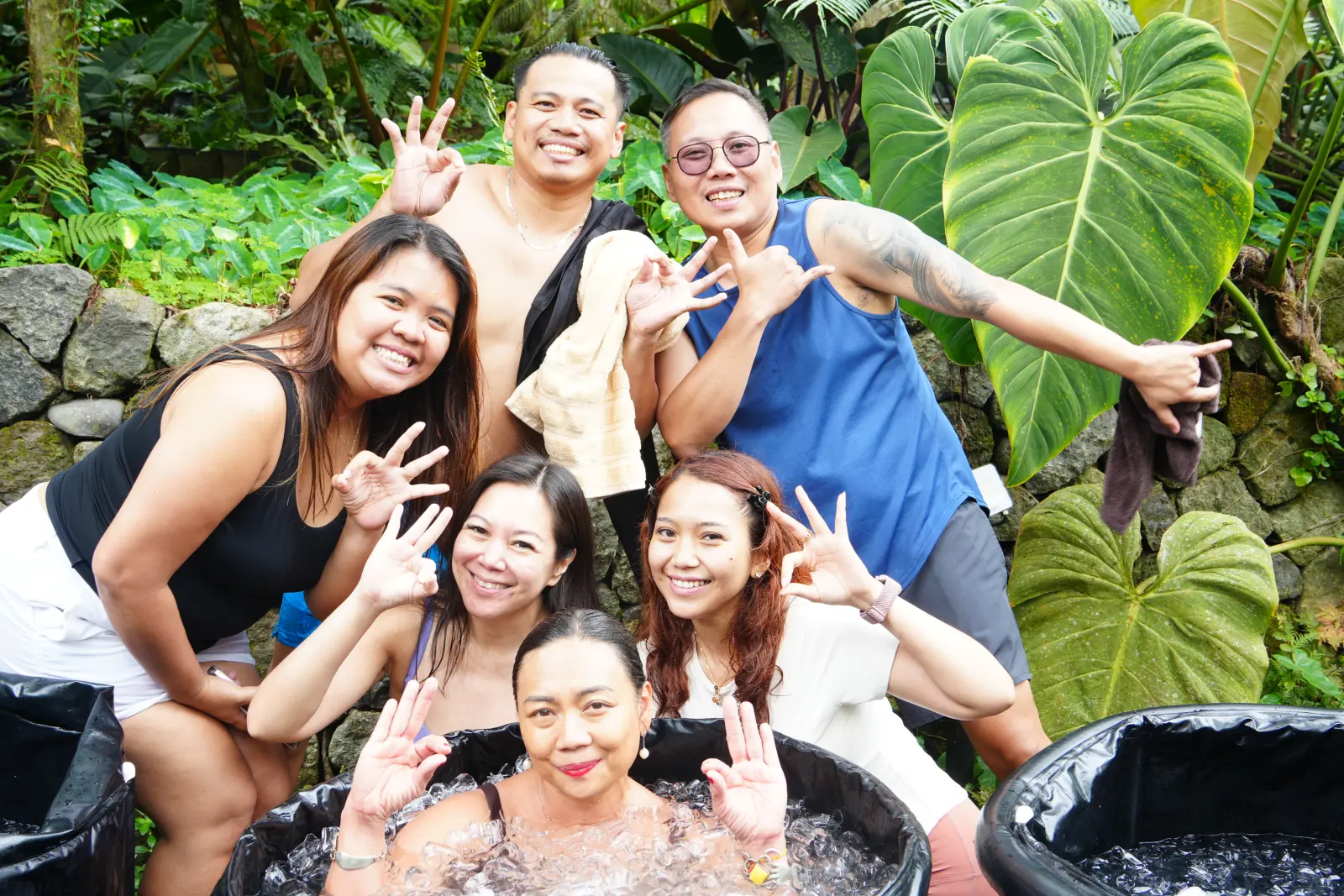 A barkada smiling and making OK signs around a friend in the ice tub